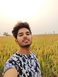 Portrait of young man looking away on field