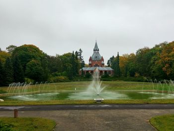 Fountain in front of garden against sky