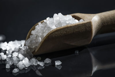 Close-up of sugar in wooden spoon against black background