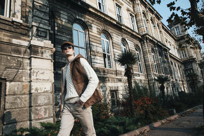 Portrait of young man standing against building in city