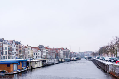 Canal amidst buildings in city against clear sky