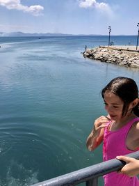 Girl standing by sea against sky