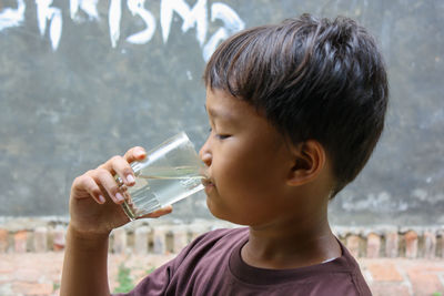 Boy is drinking water using a glass