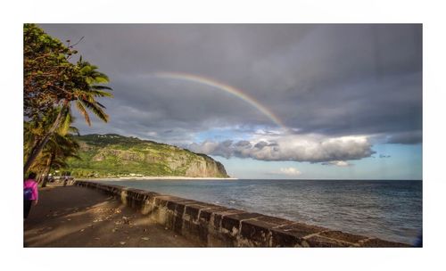 Scenic view of rainbow over sea against sky