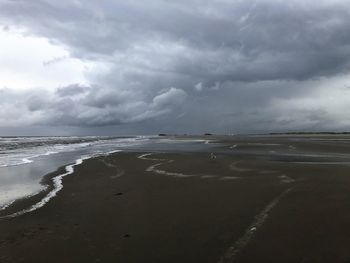 Scenic view of beach against cloudy sky