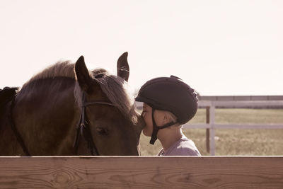 Rear view of woman riding horse in stable