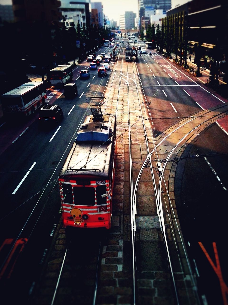 transportation, city, building exterior, architecture, built structure, high angle view, mode of transport, traffic, city life, land vehicle, street, car, illuminated, city street, railroad track, the way forward, travel, night, diminishing perspective, road