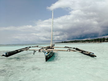 Fishing boat on beach by sea against sky