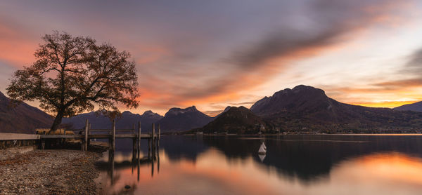 Scenic view of lake by mountains against orange sky