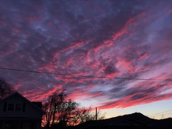 Low angle view of silhouette trees and buildings against sky during sunset