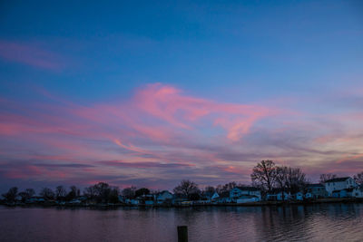Scenic view of lake against cloudy sky at sunset