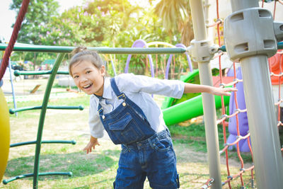 Portrait of smiling girl standing by play equipment at park