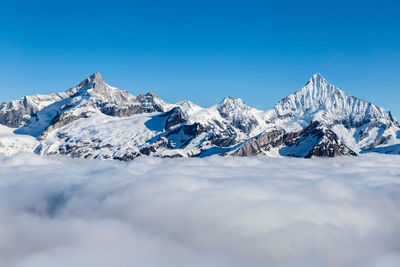 Scenic view of snowcapped mountains against blue sky