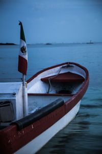 Scenic view of a boat with mexico flag and sea against sky