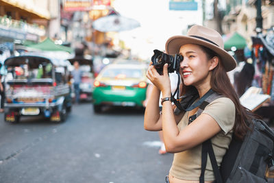 Young woman photographing on city street