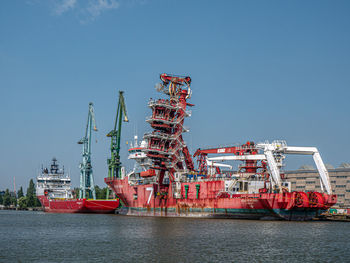 Cranes at commercial dock against clear sky