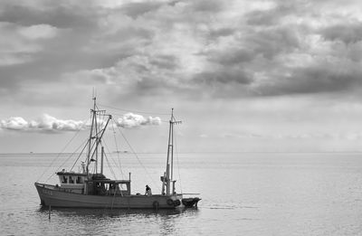 Boats in sea against cloudy sky