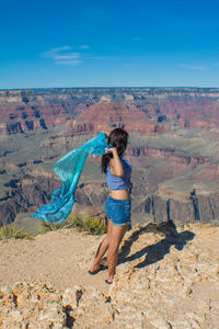 Rear view of woman standing on mountain against sky