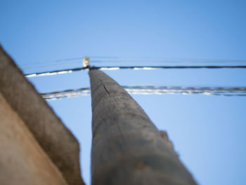 Low angle view of telephone pole against clear blue sky