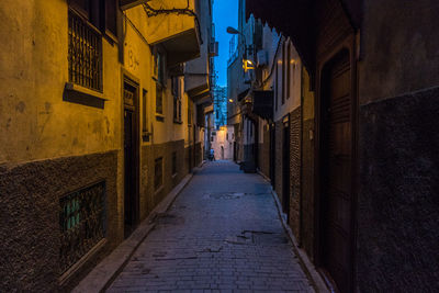 Narrow alley amidst buildings in city at night