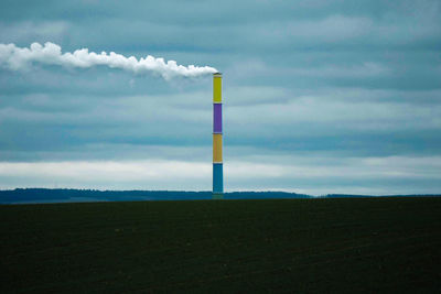 Smoke emitting from chimney on field against sky