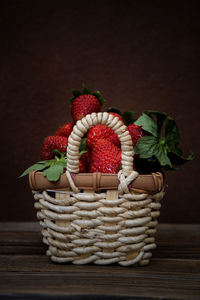 Small basket with strawberries on dark background