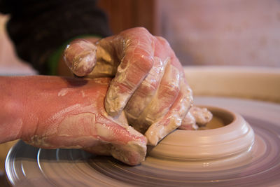 Cropped hands making clay pot