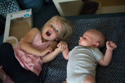 Sister with cute baby boy on bed at home