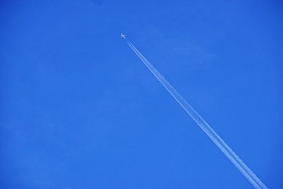 Low angle view of vapor trails in blue sky