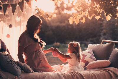 Mother and daughter sitting on bed at park