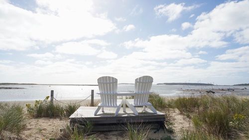 Chairs on beach against sky