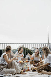 Friends enjoying adundant picnich on rooftop trerrace