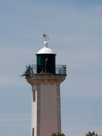 Low angle view of lighthouse by building against sky