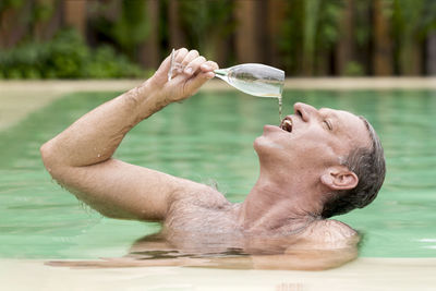 Man having drink while swimming in pool