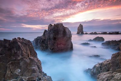 Scenic view of rocks in sea against sky during sunset