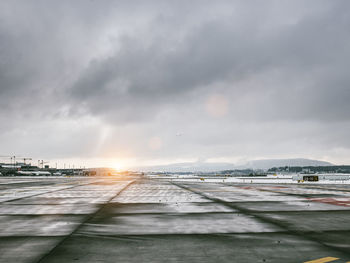 Airport runway against cloudy sky during sunset