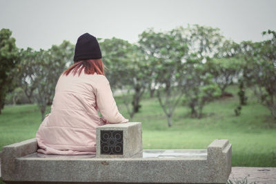 Rear view of woman sitting on bench in park