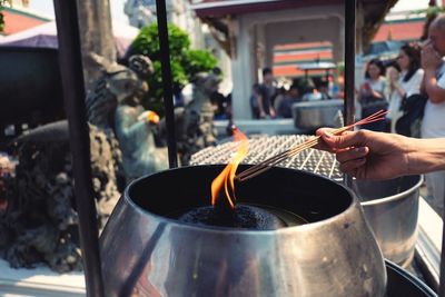 Close-up of cropped hand lighting incense