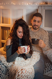 Young woman drinking coffee while sitting at home