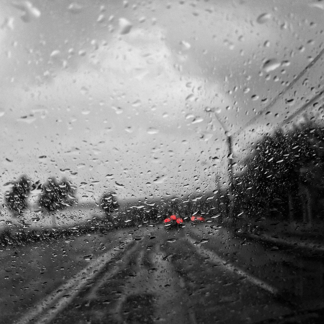 CARS ON ROAD SEEN THROUGH WET WINDOW