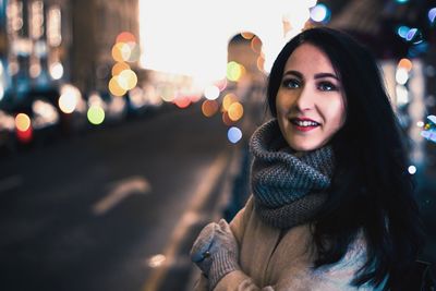 Smiling young woman on street in city during winter