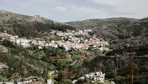 Aerial view of townscape by mountain against sky