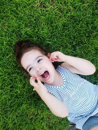 High angle view of cute girl screaming while looking away on grassy land