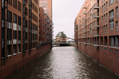 Bridge over canal amidst buildings against clear sky