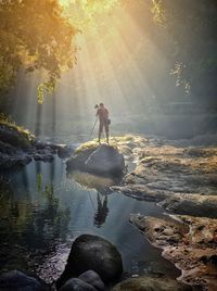 Man standing on rock against waterfall