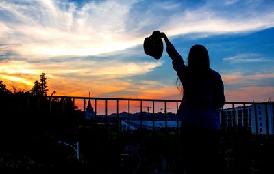 Silhouette man photographing woman by sea against sky during sunset