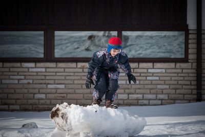 Boy playing on snow covered yard during winter