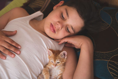 Boy with kitten sleeping on bed at home