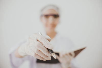 Scientist holding pen and book standing against white background