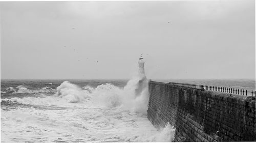 Waves splashing on shore against sky